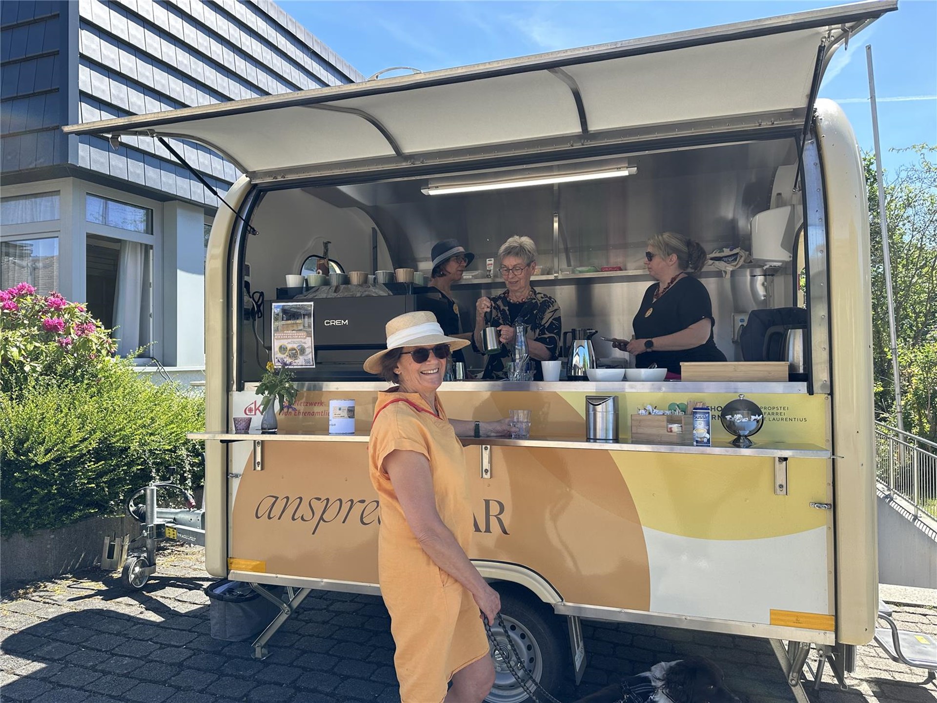 eine Frau steht vor einer mobilen Kaffee-Bar mit 3 Verkäuferinnen